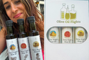 Claudia Hanna-Veysel, founder of Olive Oil Flights, holding three bottles of Egyptian Shemlaly, Moroccan Picholine, and Tunisian Chetoui extra virgin olive oil, next to a box of our North African Flight collection