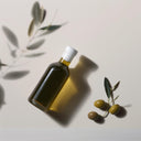 A bottle of olive oil and some olives on a white background